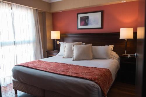 a bedroom with a large bed with red walls at Premium Tower Suites Mendoza in Mendoza