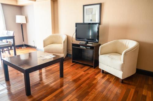 a living room with two chairs and a flat screen tv at Premium Tower Suites Mendoza in Mendoza
