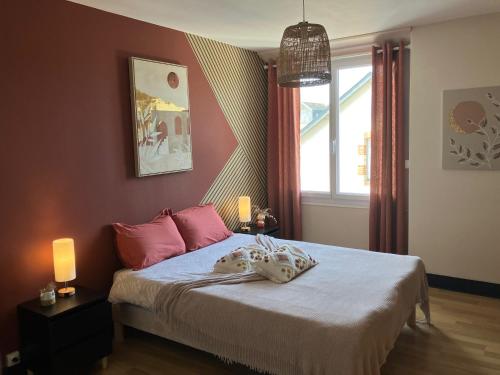 a bedroom with a bed with pink pillows and a window at Parenthèse de rêve - Piscine & confort au Mans in Coulaines
