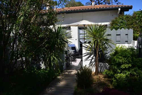 a white house with a table and an umbrella at La Villa du Grand Large in Biscarrosse