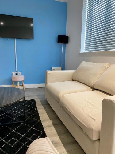 a living room with a white couch and a blue wall at Apartment 4 in Manchester