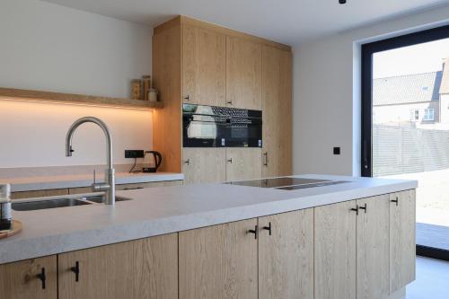 a kitchen with a sink and a large window at luxurious home in Oud-Turnhout