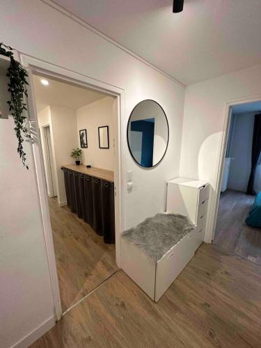Cette chambre blanche dispose d'un miroir et d'une chaise blanche. dans l'établissement Appartement spacieux aux portes du Vieux-Lille, à La Madeleine
