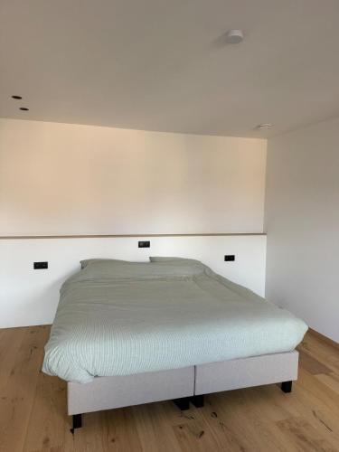 a bed in a room with white walls and wooden floors at luxurious home in Oud-Turnhout