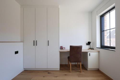 a white kitchen with a desk and a chair at luxurious home in Oud-Turnhout