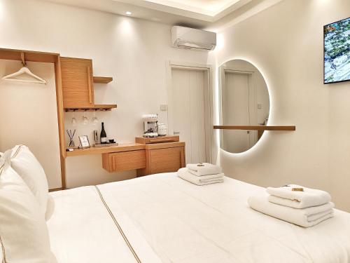 a bedroom with a white bed and a mirror at DelMar Suites Syros in Finikas