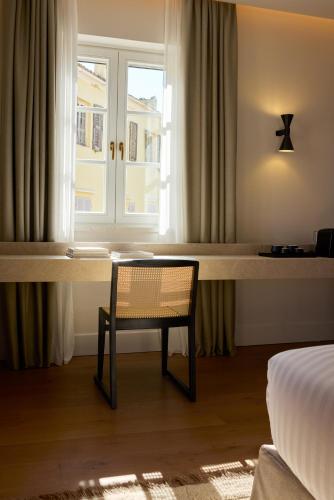 a room with a table and a chair in front of a window at The Calliston in Corfu Town