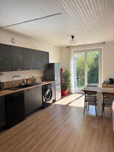 une cuisine avec des armoires noires et une table avec des chaises dans l'établissement Maison de village avec exterieur -Luberon - Villelaure, à Villelaure