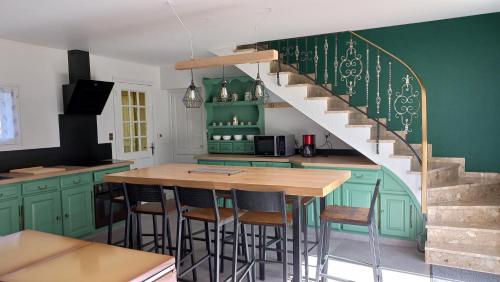 une cuisine avec des armoires vertes et un escalier dans l'établissement Gîte Chez Léon, à La Chaze-de-Peyre