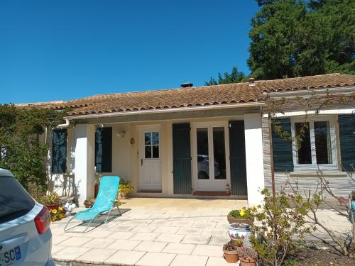 une petite maison blanche avec une chaise bleue sur un patio dans l'établissement Maison en campagne, au Thor
