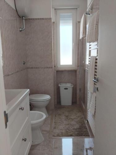 a bathroom with a toilet and a sink and a window at Villa Incanto Pina - Torre Canne in Torre Canne