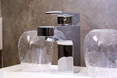 a bathroom sink with a faucet and two glasses at Spatalla Holiday Homes in Kleinmond