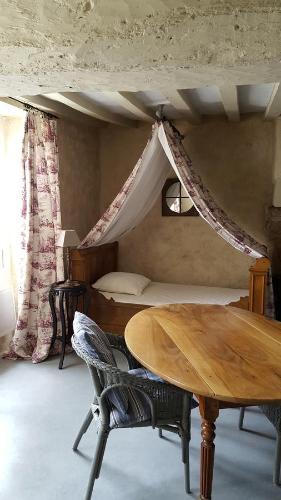 - une chambre avec une table et un lit à baldaquin dans l'établissement Domaine de la Crapaudine, à Rosnay