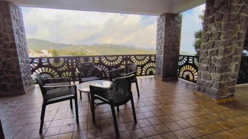 a patio with a table and chairs on a balcony at ST Kodai Heaven Stay in Kodaikānāl