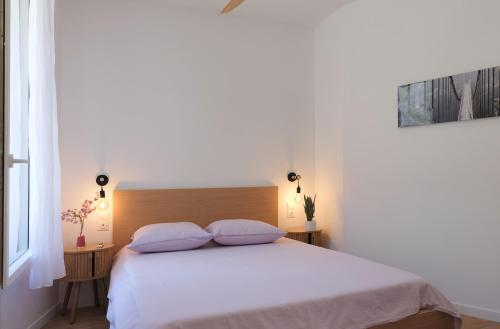 une chambre avec un lit blanc avec deux oreillers dans l'établissement La Glycine, à Aigues-Vives