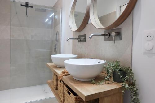 La salle de bains est pourvue de 2 lavabos blancs sur un comptoir en bois. dans l'établissement La Glycine, à Aigues-Vives