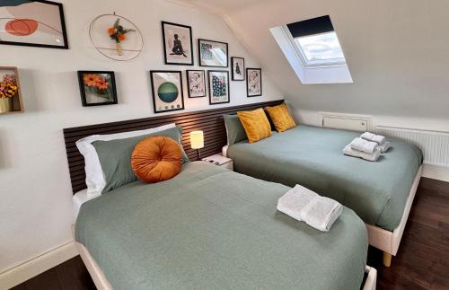 two beds in a room with pictures on the wall at Superb Studio Loft 30min to Central London in London