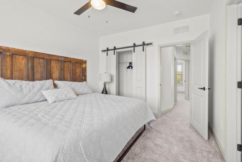 a white bedroom with a large bed and a ceiling fan at Brick Beauty Downtown, 3BR, Fenced Yard, Garage! in Cedar Falls