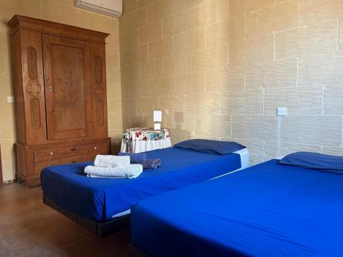 two beds in a room with blue sheets and a cabinet at Villa farmhouse with large private pool Gozo in Qala
