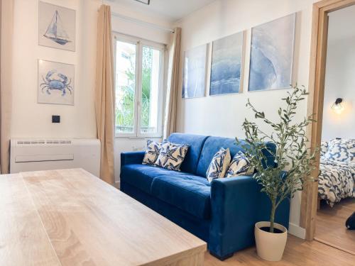 un canapé bleu dans un salon avec une table dans l'établissement Suite Palmiers bleus Cannes, à Cannes