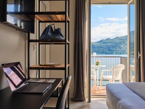 a hotel room with a laptop on a desk with a balcony at Hotel Carillon in Baveno