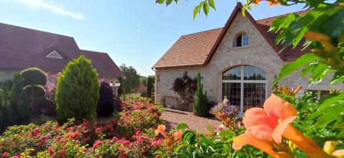 une maison avec un jardin fleuri devant elle dans l'établissement Chez Sophie, à Serbannes