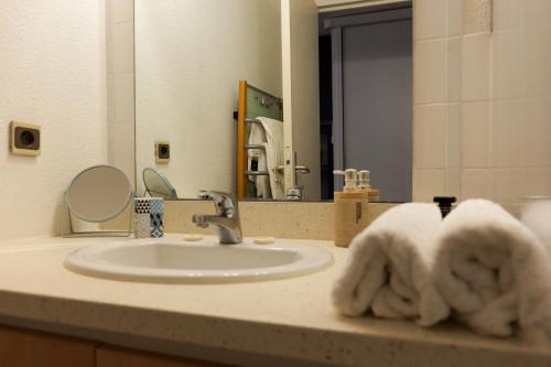 La salle de bains est pourvue d'un lavabo et de serviettes. dans l'établissement Appartement Piscine Front de mer 43 m2, Sète, à Sète