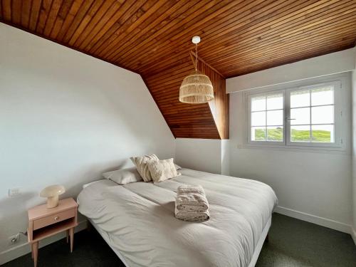a bedroom with a large bed with a wooden ceiling at Maison plage à pied in Clohars-Carnoët