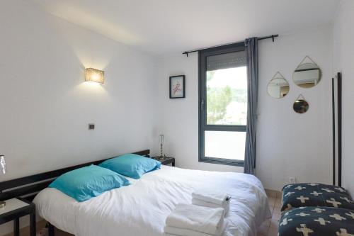une chambre avec un lit avec des oreillers bleus et une fenêtre dans l'établissement Appartement Piscine Front de mer 43 m2, Sète, à Sète