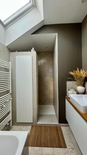 une salle de bain avec un lavabo, une baignoire et un miroir dans l'établissement L'Oasis de Coulaines - Élégance & piscine, à Coulaines