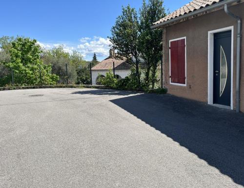 a driveway in front of a house with a red door at Les Capucines, comme chez soi, loin de chez soi in Aubenas
