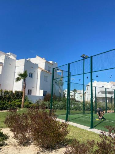 a man is playing on a tennis court behind a fence at Apartamento en Costa Ballena in Chipiona