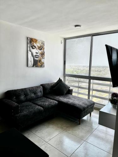 ein Wohnzimmer mit einem schwarzen Sofa und einem großen Fenster in der Unterkunft Apartamento con hermosa vista en Barranquilla in Puerto Colombia