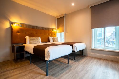a bedroom with two beds and a large window at Euston Square Hotel in London