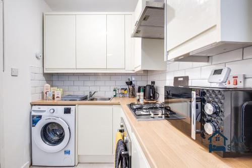 a kitchen with white cabinets and a washer and dryer at West House 4-bed Perfect for Contractors, Groups and Families in West Bromwich