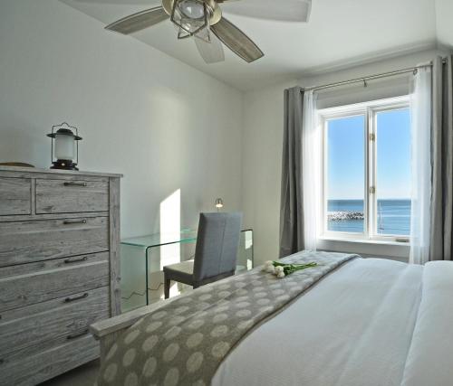 a bedroom with a bed and a desk and a window at Villa et spa - Le coeur de la plage - Charlevoix ! in Saint-Irénée