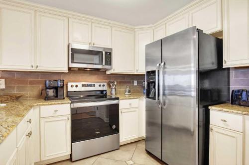 a kitchen with white cabinets and a stainless steel refrigerator at Brass Rail Condo 204 in Tybee Island