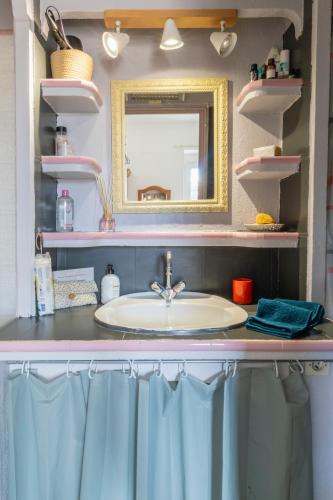 une salle de bain avec un lavabo et un miroir dans l'établissement Petite maison de ville avec cour privée & clim près Arènes MaisonCarréeConciergerie, à Nîmes