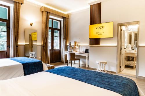 a hotel room with two beds and a desk at voco Royalty Puebla Downtown by IHG in Puebla