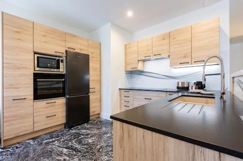 une cuisine avec un réfrigérateur noir et des armoires en bois dans l'établissement exceptional apartment with private parking, à Frontignan
