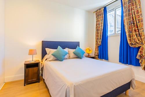 a bedroom with a large bed with blue curtains at exceptional apartment with private parking in Frontignan