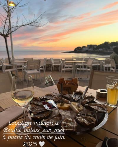 une table avec une assiette de nourriture et un verre de vin dans l'établissement Maison Le Verger de Manou, à Saint-Palais-sur-Mer