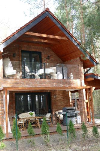 a large brick house with a porch and a patio at Ceglany Domek z jacuzzi, nad jeziorem, przy lesie in Tomaszkowo