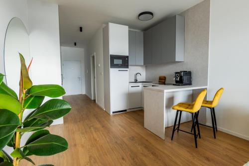 a kitchen with white cabinets and yellow chairs in a room at Apartmán Blue Wave in Banka