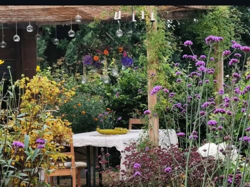 a garden with a table and many flowers at The Oaks Glamping - Jasper's Shepherds Hut in Colkirk