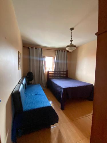 a bedroom with two beds and a couch and a window at Amplo APT próximo a lagoa/centro in Araruama