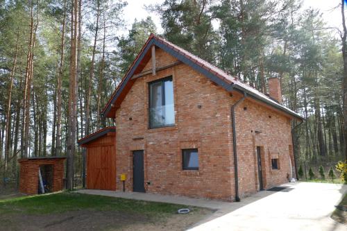 a brick house in the middle of a forest at Ceglany Domek z jacuzzi, nad jeziorem, przy lesie in Tomaszkowo