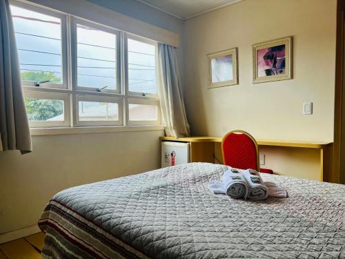 a bedroom with a bed and a red chair at Hotel Cesa in São José dos Ausentes