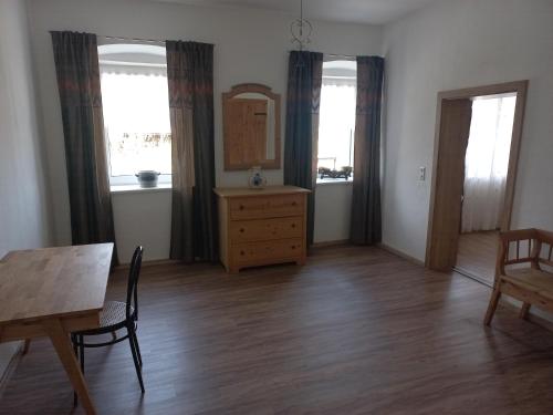 a living room with a table and a dresser and two windows at Apartment Kogler in Globasnitz