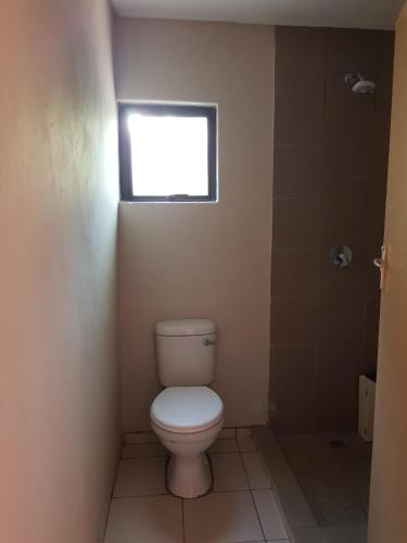 a bathroom with a toilet and a window at Maun self-catering unit in Maun